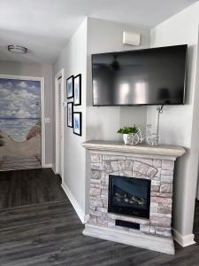 sala de estar con chimenea de piedra y TV de pantalla plana en Change in Attitude - 2BR Condo Golfin’, Fishin’, Beachin’ Everyday, en Edisto