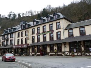 een gebouw met een rode auto ervoor geparkeerd bij Auberge d'Alsace Hotel de France in Bouillon