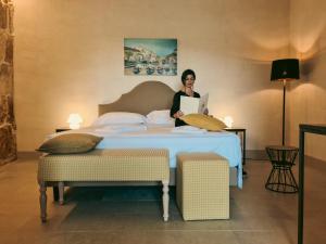 a man sitting on a bed in a hotel room at Relais Terre di Romanello in Noto