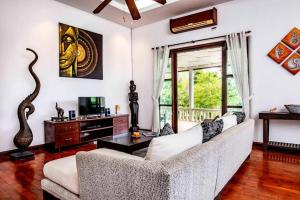 een woonkamer met een witte bank en een televisie bij Surin villa in Surin Beach