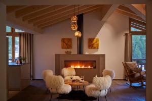 un soggiorno con sedie bianche e camino di La Vue Luxury Living Apartments a Zermatt
