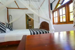a bedroom with a bed and a table and windows at Green Villa Apartment in Unawatuna