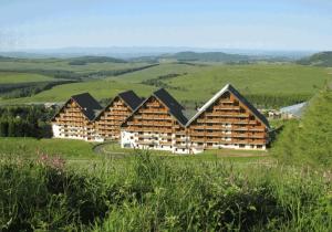un gran edificio de cabaña de madera en una colina con vistas en SUPER-BESSE Charmant T2 Piscine chauffée & Parking couvert, en Besse-et-Saint-Anastaise