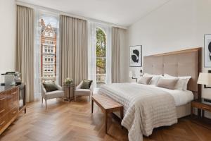 a bedroom with a large bed and a large window at The Queens Gate Hotel in London
