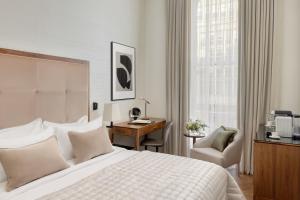 a bedroom with a bed and a desk and a chair at The Queens Gate Hotel in London