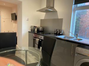 a kitchen with a glass table and a sink at Cosy 2 Bed Flat 1 in Bridgend in Bridgend