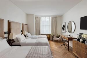 a hotel room with two beds and a desk and a mirror at The Queens Gate Hotel in London
