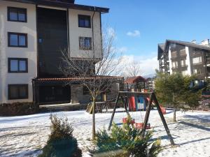 a playground in front of a building in the snow at The View Apartment, Terra Complex neighbour building in Bansko