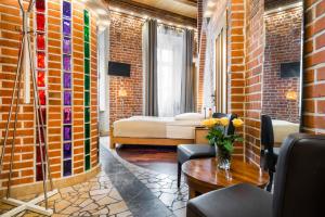 a room with a brick wall with a bed and a table at Aparthotel Stare Miasto in Kraków