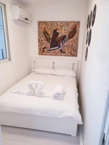 a white bed in a room with a painting on the wall at סוויטת כוכב הים ומרפסת גן מול גלי הים ומדרגות ישר לחוף העונות in Netanya