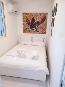 Una cama blanca en una habitación con un cuadro en la pared en כוכב הים וילה מול הגלים וברכה פרטית סגורה, en Netanya