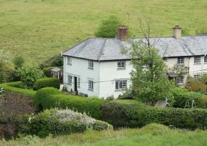 a large white house in a green field at Cedra Cottage - Vintage Country Hideaway in Axminster