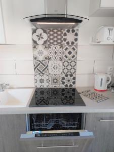 La cocina está equipada con fogones y azulejos. en Le Pré Fleuri à Guillestre - Appartements neufs classés Meublés de Tourisme 3 étoiles - Parking privatif, en Guillestre
