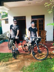 two men standing with their bikes in front of a house at Dinesh Safari Homestay in Udawalawe