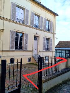 a house with a red ribbon in front of a fence at Studio de 23 m² au centre de Montfort L'amaury in Méré