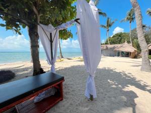 a bench on the beach with an umbrella at Sea Love Beach Bar & Bungalows in Ban Tai