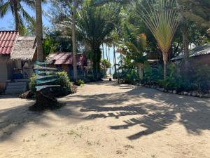 a street with palm trees and a building and a sidewalk at Sea Love Beach Bar & Bungalows in Ban Tai