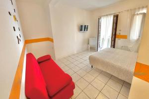 Sofá rojo en una habitación con cama en Albergo Vittoria, en Toscolano Maderno