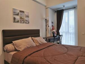 a bedroom with a large bed and a table at A Peaceful Room at Barsacity Apartment by Ciputra in Seturan