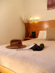 Una cama con sombrero y prismáticos. en Hotel La Tinensa, en La Pobla de Benifassà (Puebla de Benifasar)