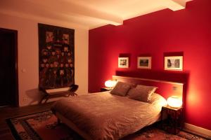 a bedroom with a red wall with a bed and two lamps at Chateau de Beaucouse in Thoard