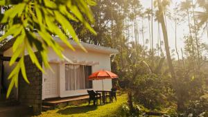 a table with an umbrella in front of a house at Silver Oak By Exuberance Stays (Independent Holiday Home) in Wayanad