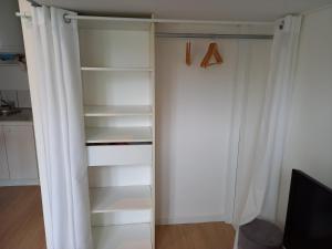 a closet with white curtains and a tv at Studio avec terrasse en résidence calme à Dijon. in Dijon