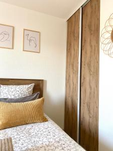 a bedroom with a bed and a wooden closet at Appartement en face Hopital Nord in Saint-Priest-en-Jarez