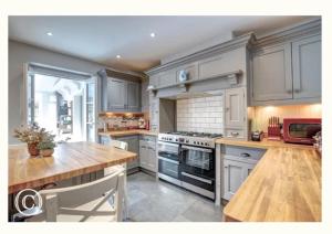 une cuisine avec des placards blancs et une table en bois dans l'établissement Charming 3-Bed Cottage in Swanage, à Swanage