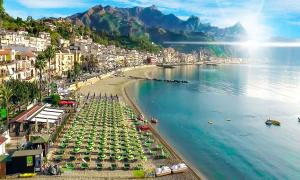 a beach with chairs and umbrellas in the water at B&B Marranzano in Giardini Naxos