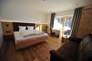 a bedroom with a bed and a couch and a window at Hotel Regnum Zegg in Nauders