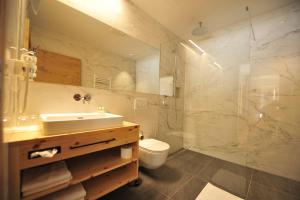 y baño con lavabo, aseo y ducha. en Hotel Regnum Zegg, en Nauders
