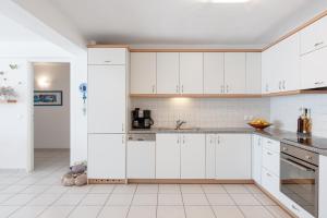 a kitchen with white cabinets and white tile floors at Beachfront Modern Apartment in Eretria