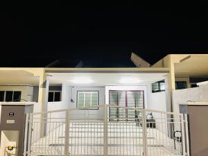 a white house with a gate and windows at night at HOMESTAY PD in Port Dickson