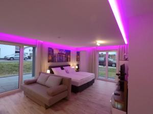 a bedroom with a bed and a couch and pink lighting at -Neubau- 68 qm 2-Zimmer-Wohnung in Fulda