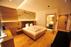 a bedroom with a bed and a stone wall at Hotel Regnum Zegg in Nauders