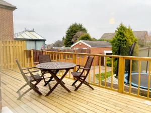 a wooden deck with a table and chairs on it at Noknokstay-Highstone House,4 Bedrooms, Garden with Parking, Great for Longer Stay in Barnsley