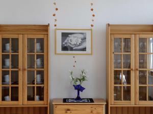a vase with flowers on a table next to two cabinets at Oase am See in Waren