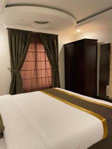 a bedroom with a large white bed and a window at Arrawiya Alzahabia Hotel in Dammam