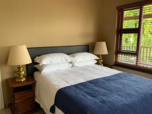 a bedroom with a bed with pillows and two lamps at Marina Views Guesthouse in Hartbeespoort