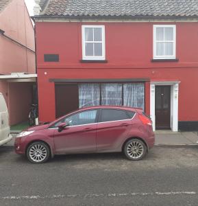 a red car parked in front of a red house at Seaview Cottage 24 Freeman Street in Wells next the Sea
