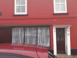 un bâtiment rouge avec une voiture garée devant lui dans l'établissement Seaview Cottage 24 Freeman Street, à Wells-next-the-Sea 4 autres photos
