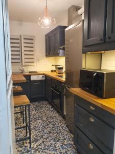 a kitchen with black cabinets and a microwave at Bel appartement 2 pièces, sortie de métro ligne 8 in Charenton-le-Pont