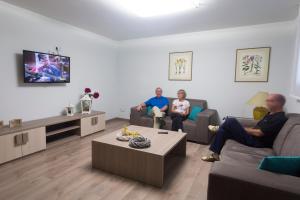 tres personas sentadas en una sala de estar viendo la tele en Hotel Rural Auñamendi, en Ochagavía