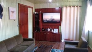 a living room with a couch and a flat screen tv at Casa de temporada da vovó in Urubici