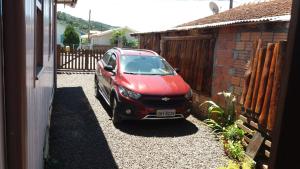 un coche rojo estacionado en la entrada de una casa en Casa de temporada da vovó, en Urubici