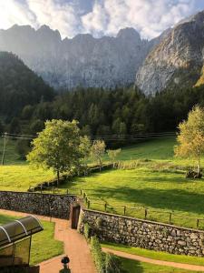 a stone wall next to a green field with mountains at Bilocale con box a due passi dalle piste da sci in Colere