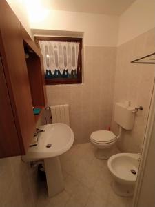 a bathroom with a white toilet and a sink at Bilocale con box a due passi dalle piste da sci in Colere +14 photos