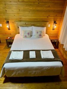Schlafzimmer mit einem großen Bett und Holzwänden in der Unterkunft Pousada Costaneira in Cambará