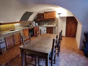 a large kitchen with a wooden table and chairs at Chambre Cévennes: Piscine, lamas, rivière in Cros